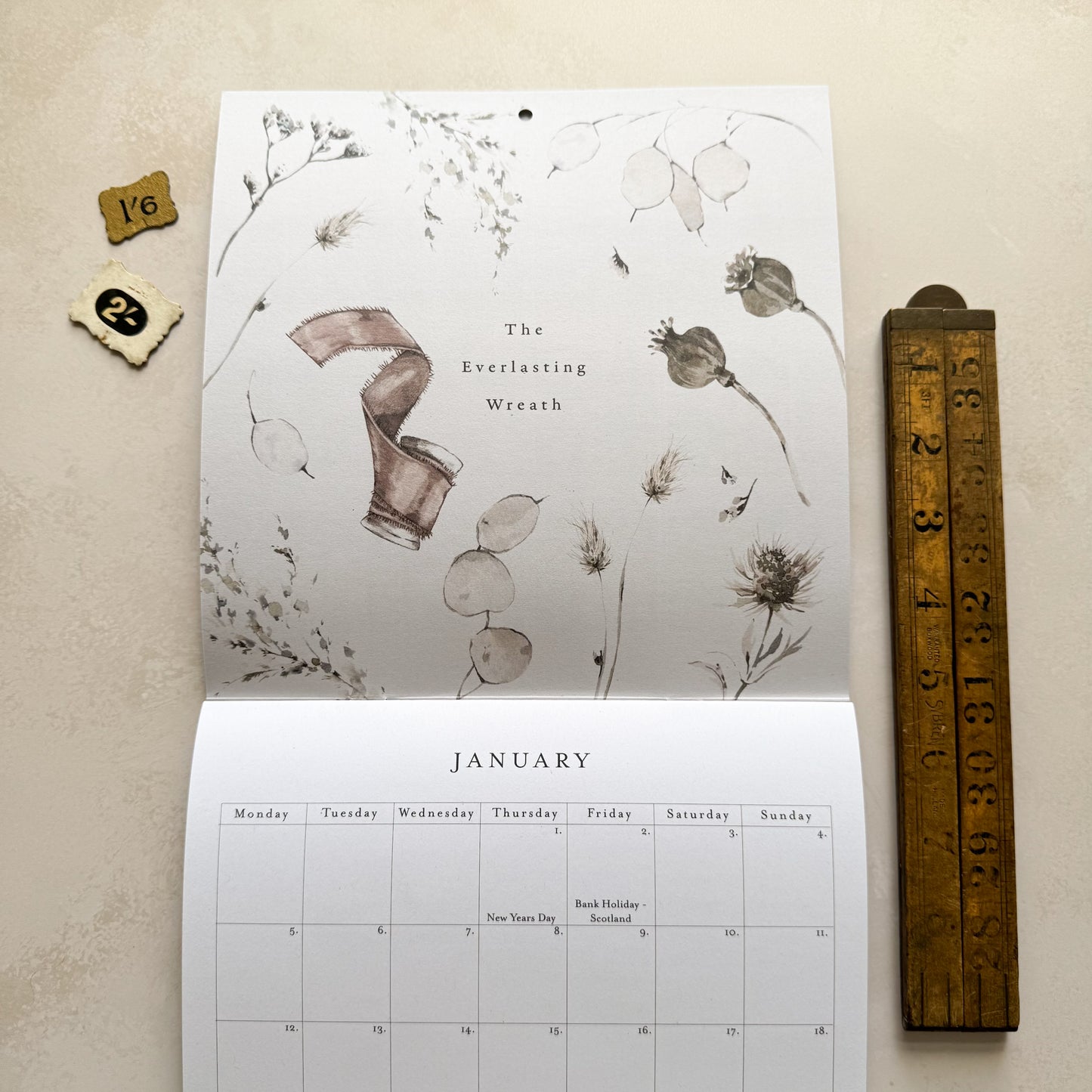 Calendar with floral design and wooden ruler on a beige surface