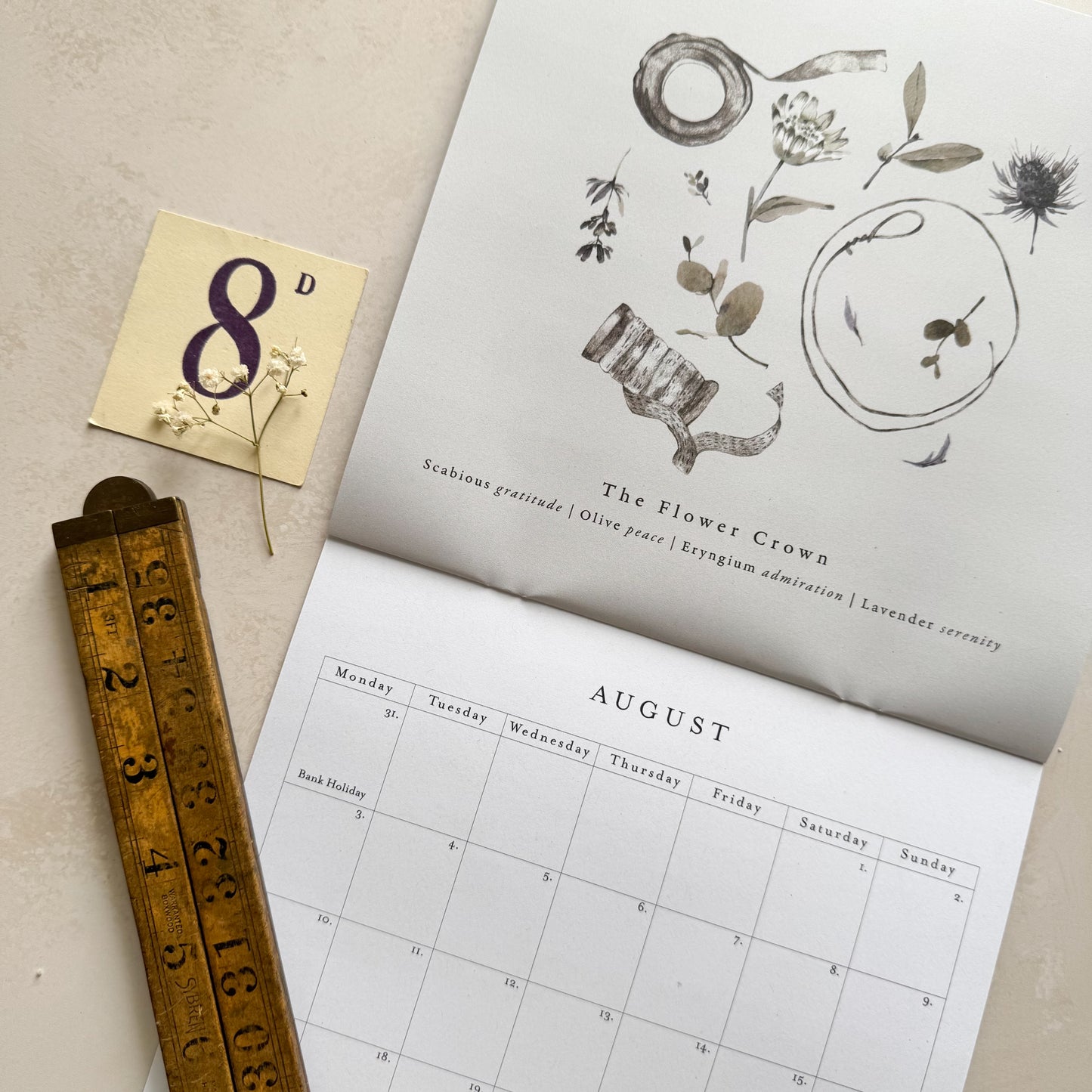 Calendar with floral design, small card with number 8, and ruler on a textured surface