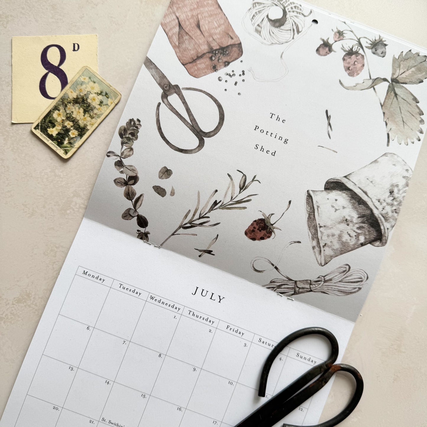 Calendar with botanical design and scissors on a beige surface